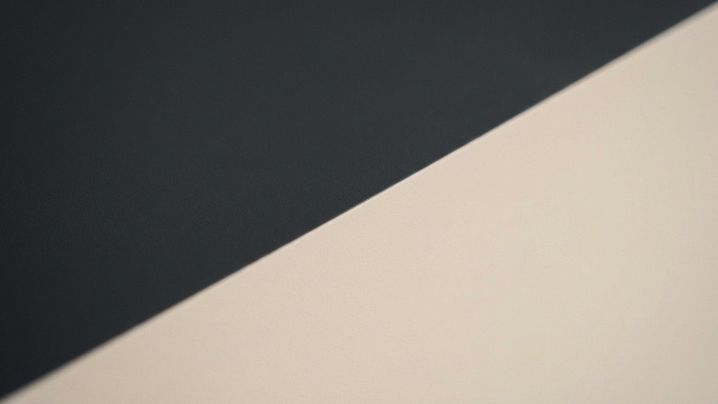 נוצר על ידי מודל בינה מלאכותית Gemini Pro Close up of a perfectly straight paint line separating a dark grey and light beige wall